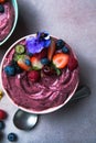 Two summer acai smoothie bowls with strawberries, blueberries, on gray concrete background. Breakfast bowl with fruit and cereal