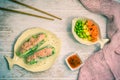 Two summer rolls with salad and salmon and sauce on a white wooden background, japanese, asian food Royalty Free Stock Photo