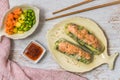 Two summer rolls with salad and salmon and sauce on a white wooden background, japanese, asian food Royalty Free Stock Photo