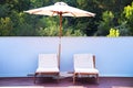 Two sun loungers under an umbrella on the outdoor patio Royalty Free Stock Photo