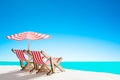 Two sun loungers under an umbrella on the sandy beach by the sea and the sky with copy space Royalty Free Stock Photo