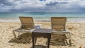 Two sun loungers and a wicker table on a tropical beach. Royalty Free Stock Photo