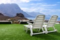 Two sunbeds chaiselongs on the sea, ocean with view on mountains