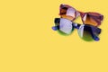 Two sunglasses on yellow background close up top view, fashionable eye sunshades, pair of trendy modern female and male eyeglasses Royalty Free Stock Photo