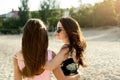 Two suntanned friends sunbathing on the beach and having fun. Girls wearing stylish swimsuits and sunglasses enjoy in Royalty Free Stock Photo