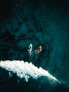 Two surfers floating on surfboard in tropical ocean with big and powerful wave behind them. Aerial top view of surfers in crystal Royalty Free Stock Photo