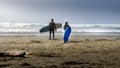 Two Surfers heading into the Fog covered Pacific Ocean at Cox Bay Beach at the Pacific Rim National Park