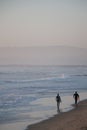 two surfers walking along the beach with surfboards in hand Royalty Free Stock Photo