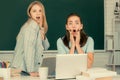 Two surprised students girls friends in classroom at school college or university on blackboard background. Learning and Royalty Free Stock Photo