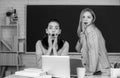 Two surprised students girls friends in classroom at school college or university on blackboard background. Learning and Royalty Free Stock Photo