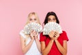 Two surprised women hiding behind the money