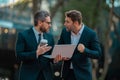 Two surprized business men team using laptop outdoor. Businessmen looking laptop with their business success in city Royalty Free Stock Photo