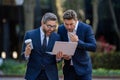 Two surprized business men team using laptop outdoor. Businessmen looking laptop with their business success in city Royalty Free Stock Photo