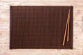 Two sushi chopsticks with empty bamboo mat or wood plate on brown wooden Background Top view with copy space. empty asian food Royalty Free Stock Photo