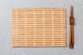 Two sushi chopsticks with empty bamboo mat or wood plate on stone Background Top view with copy stace Royalty Free Stock Photo