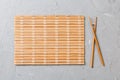 Two sushi chopsticks with empty bamboo mat or wood plate on stone Background Top view with copy stace Royalty Free Stock Photo