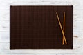 Two sushi chopsticks with empty bamboo mat or wood plate on white wooden Background Top view with copy space. empty asian food Royalty Free Stock Photo