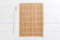 Two sushi chopsticks with empty bamboo mat or wood plate on wooden Background Top view with copy stace Royalty Free Stock Photo