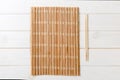 Two sushi chopsticks with empty bamboo mat or wood plate on wooden Background Top view with copy stace Royalty Free Stock Photo
