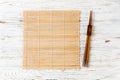 Two sushi chopsticks with empty brown bamboo mat or wood plate on white wooden Background Top view with copy space. empty asian Royalty Free Stock Photo