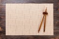 Two sushi chopsticks with empty brown bamboo mat or wood plate on wooden Background Top view with copy space. empty asian food Royalty Free Stock Photo