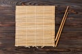 Two sushi chopsticks with empty brown bamboo mat or wood plate on wooden Background Top view with copy space. empty asian food Royalty Free Stock Photo