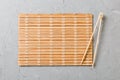 Two sushi training sticks with empty bamboo mat or wood plate on stone Background Top view with copy stace Royalty Free Stock Photo