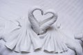 Two Swans Made Of Towels Forming Look Like Heart Shape On Bed