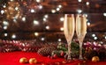 Two sweaty glasses of champagne, chocolate and Christmas decorations on red table on the side of burning garlands Royalty Free Stock Photo