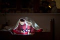 Two sweet boys, reading a book in bed after bedtime, using flash Royalty Free Stock Photo