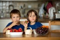 Two sweet children, boy brothers, eating fresh fruits at home