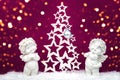 Two Christmas baby angels statuettes on snow with Christmas tree Royalty Free Stock Photo