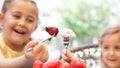 two sweet girls in the restaurant eat red strawberries with cream,Outdoor bokeh background with neutral colors. happy, friends ha Royalty Free Stock Photo