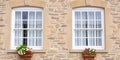 Two traditional white sash windows with flower boxes on a stone building facade Royalty Free Stock Photo