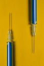 two syringes with a vaccine on a yellow background