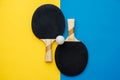 Two table tennis or ping pong rackets and ball on blue and yellow background. Top view. Copy, empty space for text Royalty Free Stock Photo