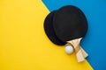 Two table tennis or ping pong rackets and ball on blue and yellow background. Top view. Copy, empty space for text Royalty Free Stock Photo