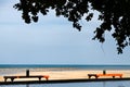 Two tables under shade and tree on the beach with ocean and pool in a scene on evening sunlight Royalty Free Stock Photo