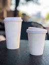 Two take away coffee mugs on the table in a cafe with copy space Royalty Free Stock Photo