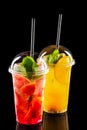 Two take away glasses with strawberry and orange lemonade