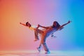 Two talented dancers mid-movement performing in vibrant pink and blue lighting against gradient background. Dynamic Royalty Free Stock Photo