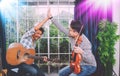 Duo of two musicians playing acoustic guitar and violin playfully hold hands.