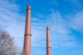 Two tall abandoned industrial chimney pipes against blue sky. Chimneys Royalty Free Stock Photo