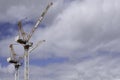 Two tall cranes with cabin against a cloudy blue sky Royalty Free Stock Photo