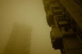Two tall residential buildings immersed in misty yellow sky. Cyberpunk stylistics.