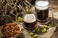 Two tankard beer with wheat and hops , basket of pretzels