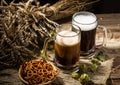 Two tankard beer with wheat and hops , basket of pretzels