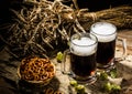 Two tankard beer with wheat and hops , basket of pretzels