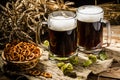 Two tankard beer with wheat and hops , basket of pretzels
