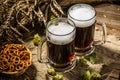 Two tankard beer with wheat and hops , basket of pretzels